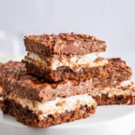 ow Krispie topped brownies stacked on a white cake plate