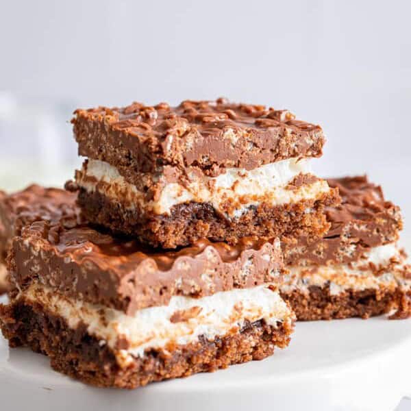 ow Krispie topped brownies stacked on a white cake plate