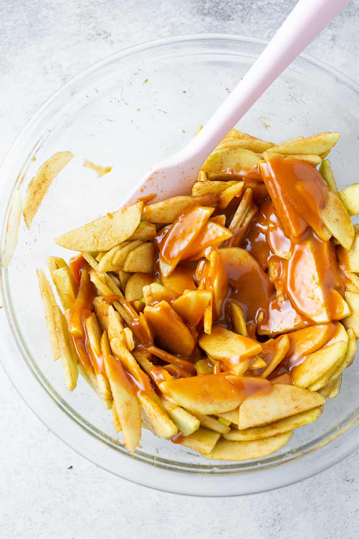 Sliced spiced apples in a bowl topped with melted caramel. 