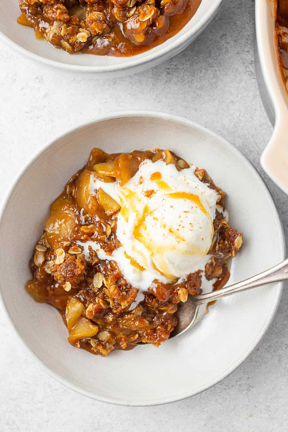 A bowl filled with caramel apple crisp topped with ice cream. 