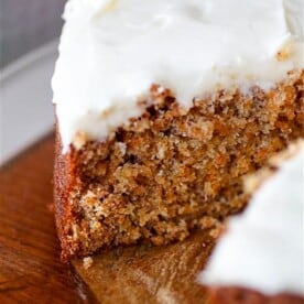 carrot cake with creamy cream cheese frosting cut with one slice missing