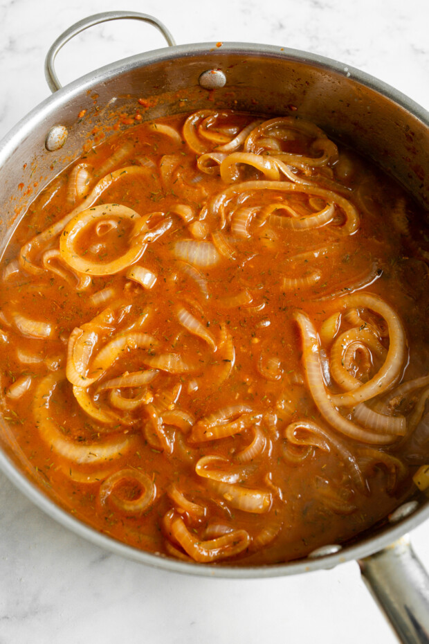 Onions in a pan with sauce for French Onion Salisbury Steak. 