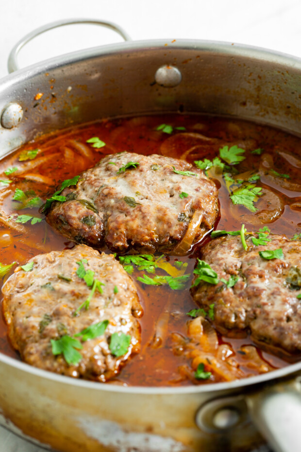 French Onion Salisbury Steak in a pan with onions. 