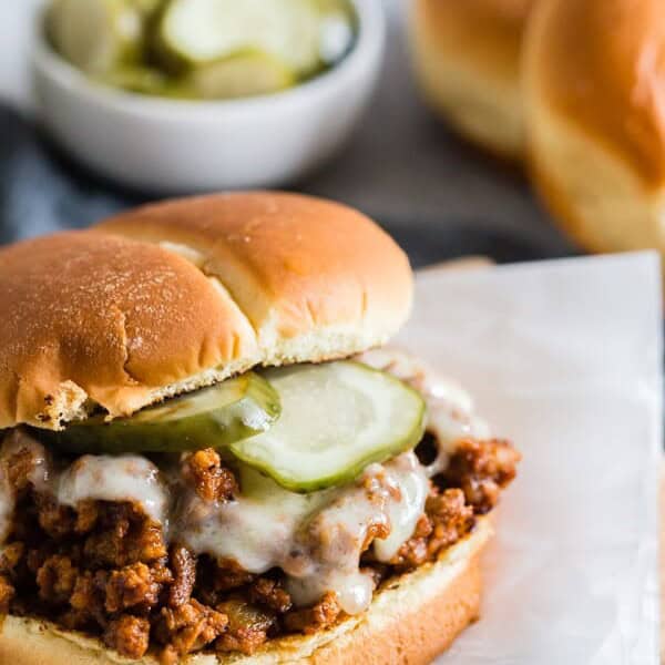 These sloppy Cubanos are the perfect spin to the traditional Sloppy Joe. A delicious mixture of ground pork, chorizo, spices, lime, and tomato piled high on a bun and topped with Swiss cheese and pickles. It's the perfect mashup of a Cuban sandwich and Sloppy Joe.