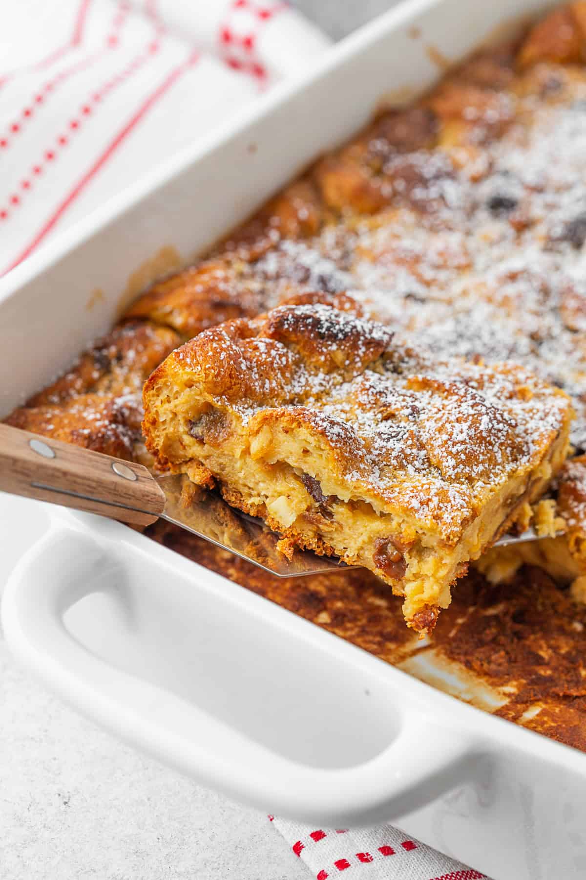 A slice of Panettone Bread Pudding being taken out of the baking dish. 