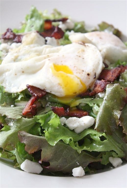 This mixed green salad with bacon, goat cheese, and fried egg is a great protein pack salad option. Made with a fresh homemade red wine vinaigrette and perfect for lunch or dinner. You'll love this easy salad! Mixed green salad with fried egg on top.