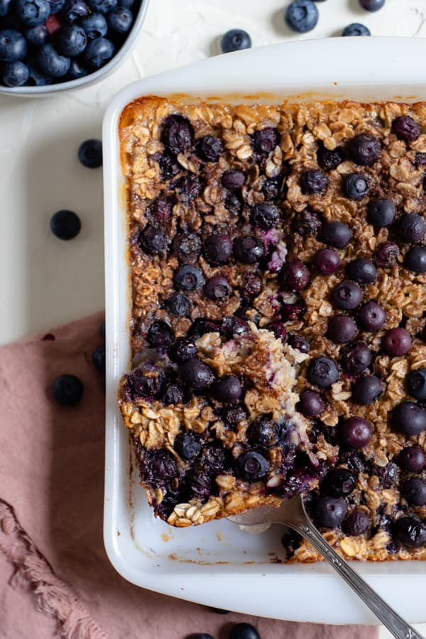 baked blueberry oatmeal in a white dish with a slice cut out