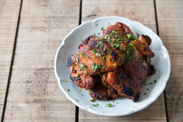 Crispy, glazed chicken thighs on a white serving plate.