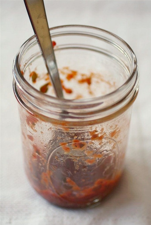 Roasted Garlic Tomato Sauce in a jar with a spoon. 