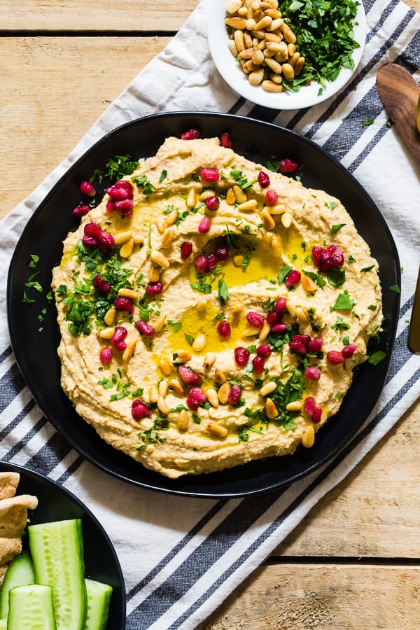Tahini Free Hummus on a plate topped with parsley, olive oil, and pomegranate seeds.