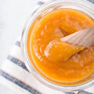 vanilla honey peach butter in a glass jar with a wooden knife