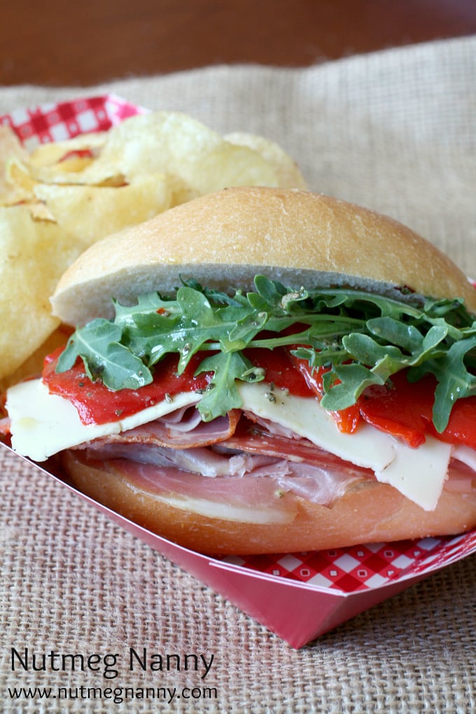 Italian Mini Sub Sandwiches with Homemade Sub Sauce by Nutmeg Nanny Closeup of Italian sub sandwich with potato chips on the side.