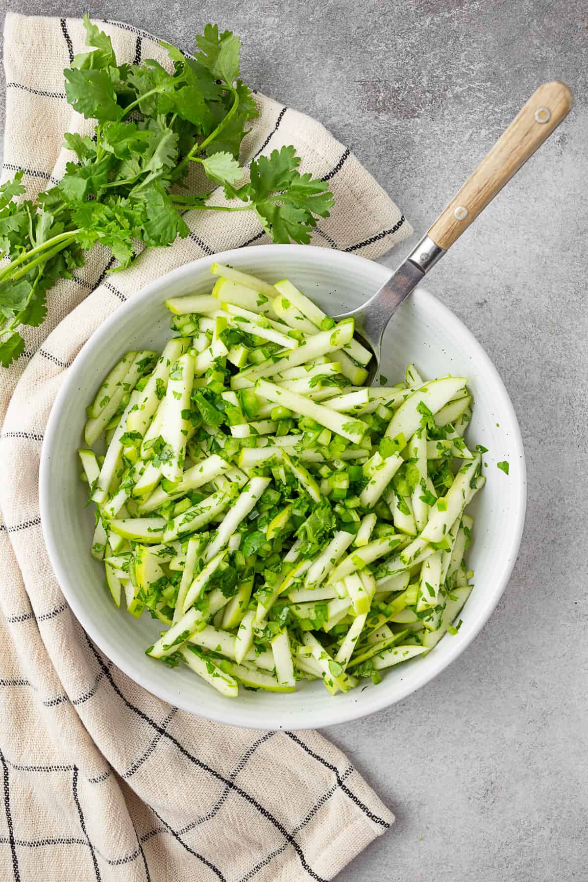 Cilantro Apple Slaw in a white bowl with a spoon .