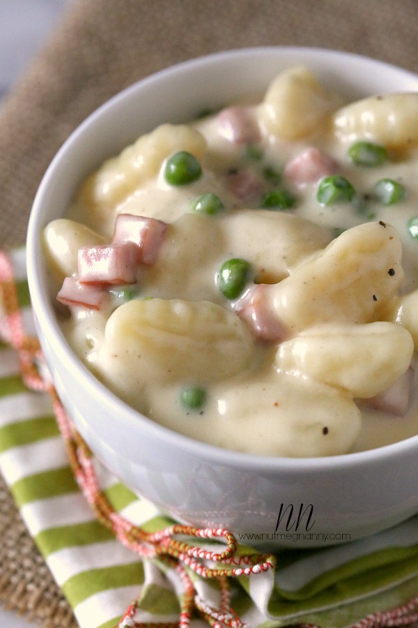 Skillet Cheesy Gnocchi with Peas and Ham in a bowl with a napkin.