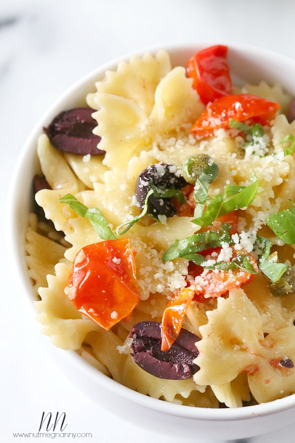 {20 Minute} Kalamata Olive, Tomato and Caper Pasta by Nutmeg Nanny Kalamata Olive, Tomato and Caper Pasta in a bowl topped with basil.