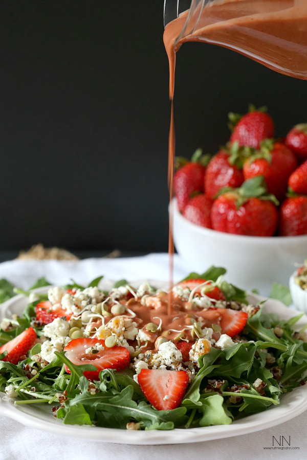 Strawberry dressing being poured onto a salad.