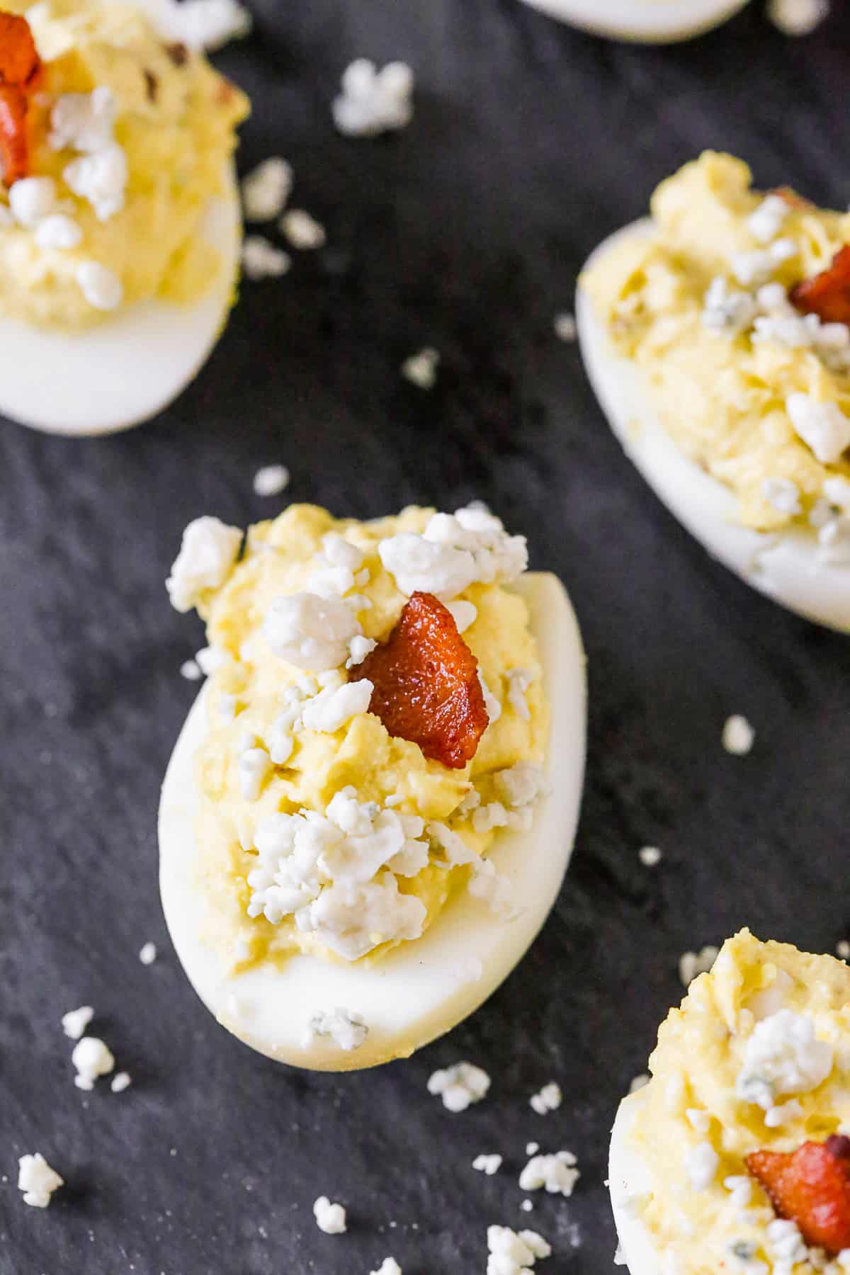 Blue Cheese Deviled Eggs garnished with extra blue cheese and bacon. 