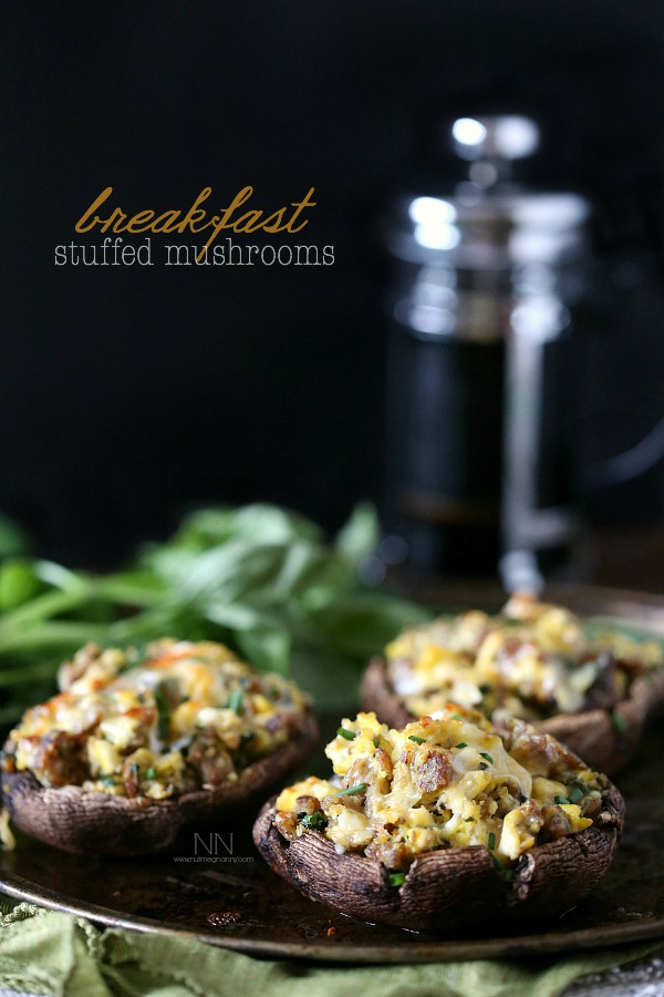 Breakfast Stuffed Mushrooms by Nutmeg Nanny Breakfast Stuffed Mushrooms sitting on a large plate with coffee in the background.