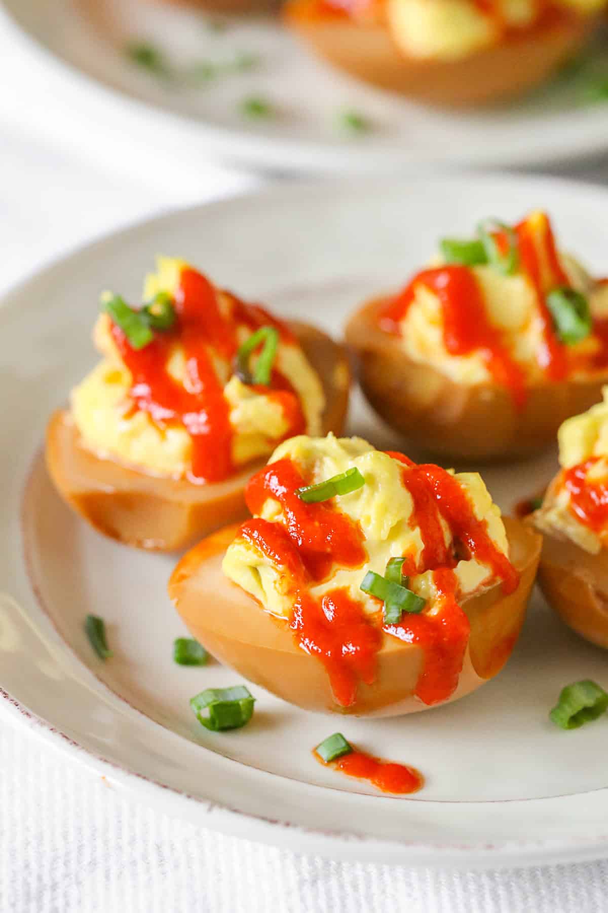 Soy Sauce Deviled Eggs on a plate drizzled with sriracha. 