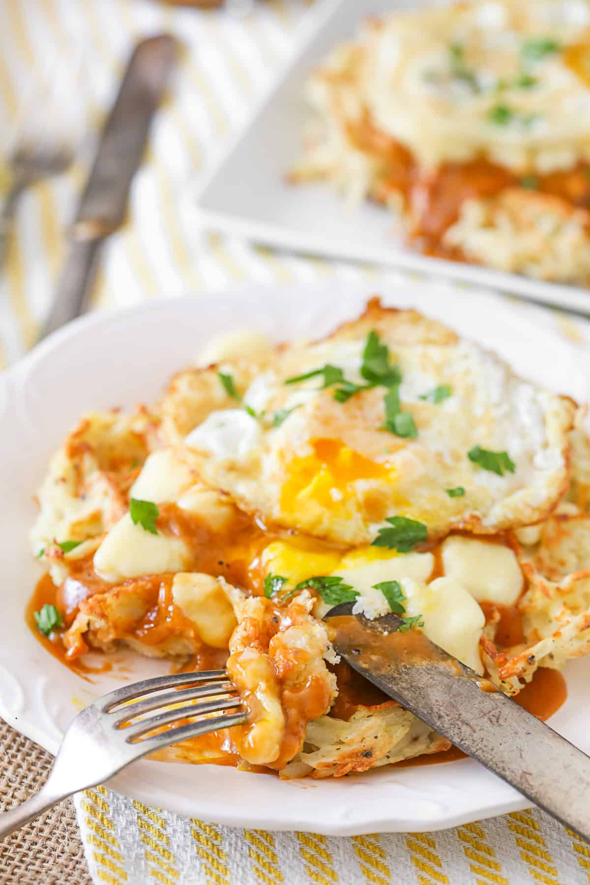 Poutine Hash Brown Waffles being cut with a knife and fork. 