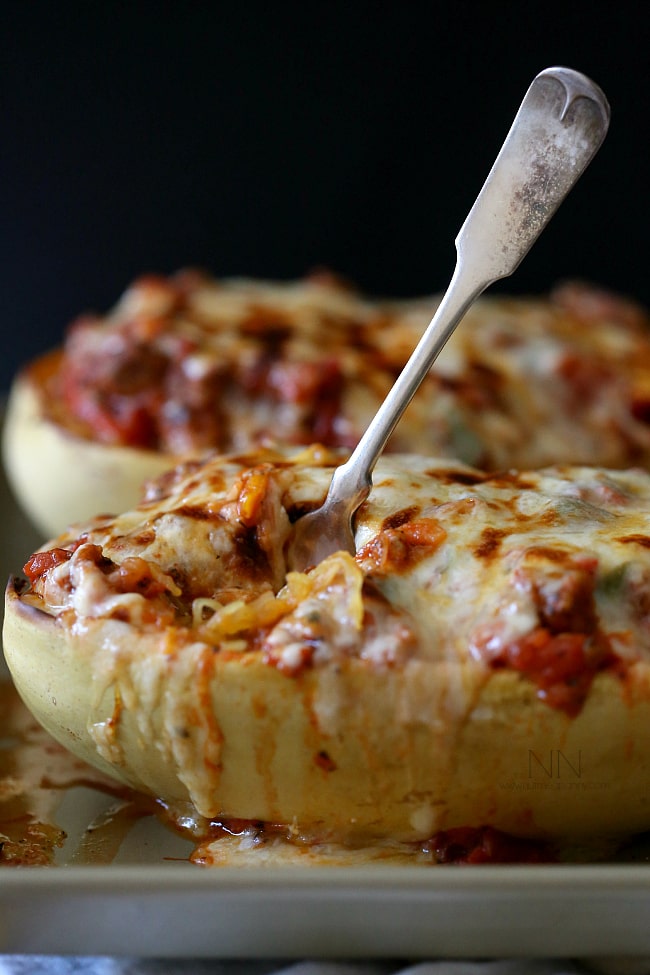This sausage and peppers stuffed spaghetti squash is the perfect way to use up all that winter squash. Deliciously filling and and super simple to make. Sausage and Peppers Stuffed Spaghetti Squash with a fork in it.