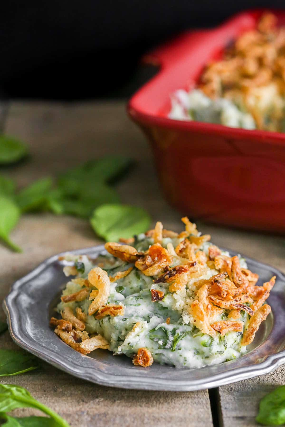 Spinach Parmesan Baked Mashed Potatoes served in a dish and scooped on a plate. 