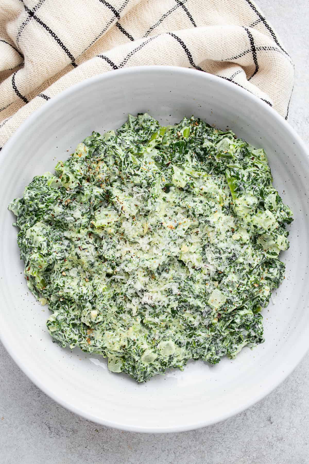 Creamed Kale in a bowl with a napkin on a table. 
