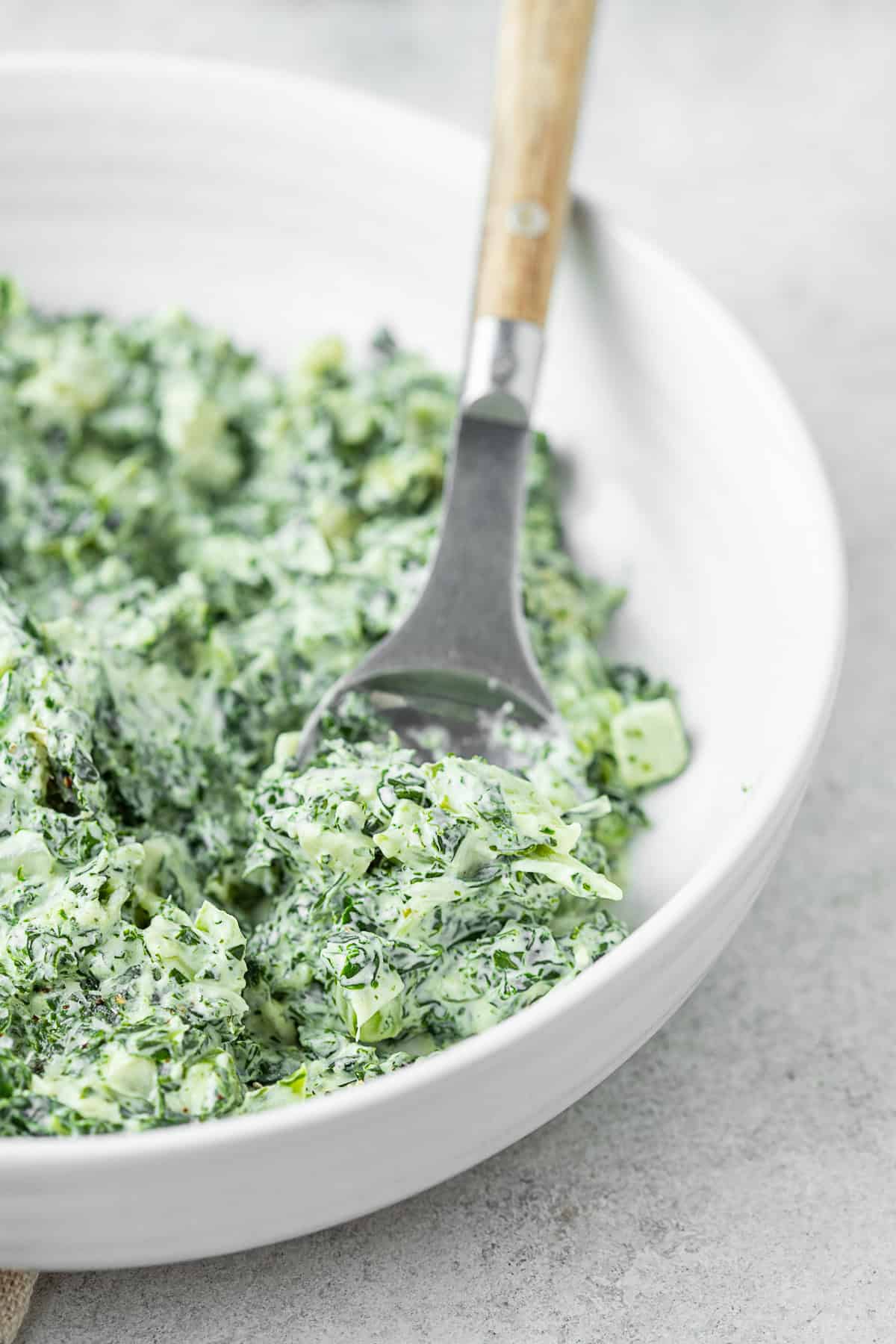 Creamed Kale in a bowl with a serving spoon. 
