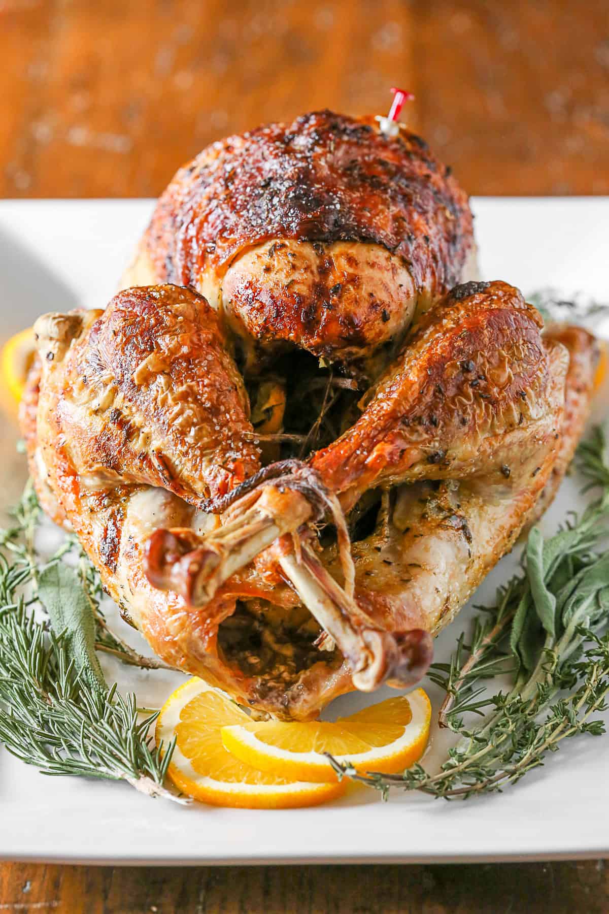 This herbed mayonnaise roast turkey is the perfect addition to your Thanksgiving table. Full of orange, sage, rosemary and thyme it's super moist and totally easy! Herbed Mayonnaise Roast Turkey served up with fresh herbs.