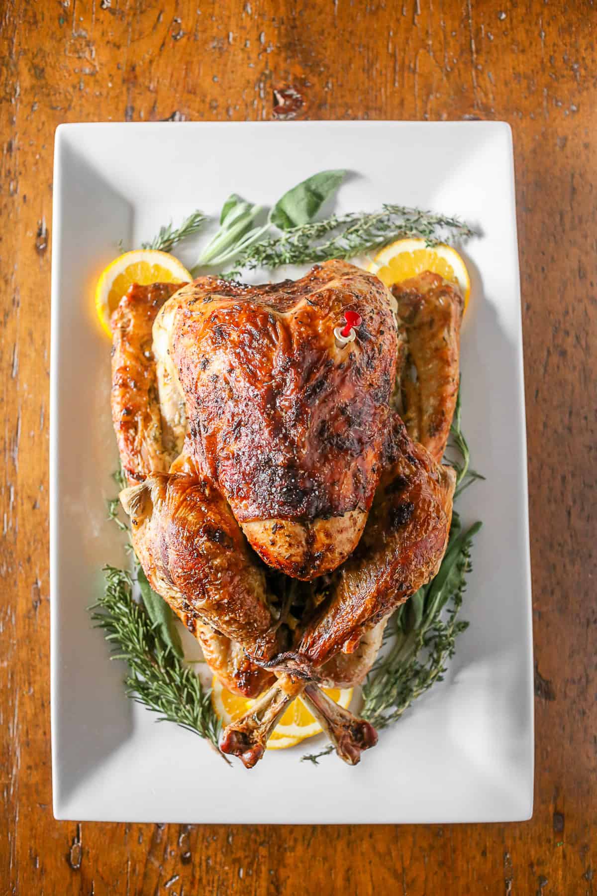 This herbed mayonnaise roast turkey is the perfect addition to your Thanksgiving table. Full of orange, sage, rosemary and thyme it's super moist and totally easy! Herbed Mayonnaise Roast Turkey on a platter.
