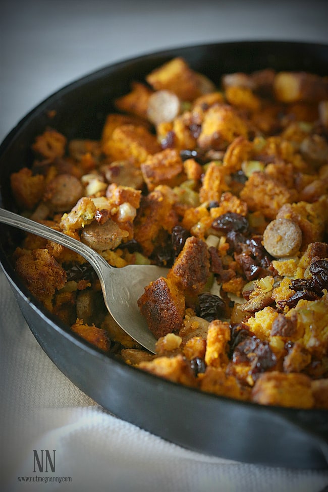 A spoon in a dish of Pumpkin Cornbread Stuffing. 