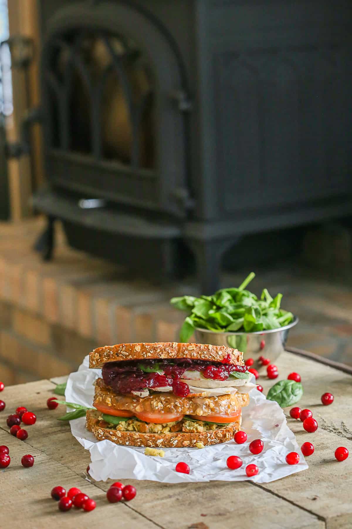 Leftover Thanksgiving Sandwich sitting on a table with a bowl of spinach in the background.