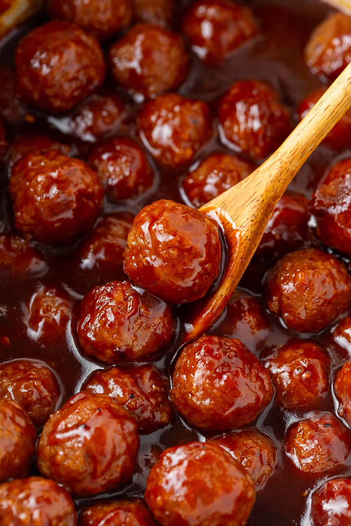 Slow Cooker Bourbon BBQ Meatballs in a crock with a wooden spoon. 