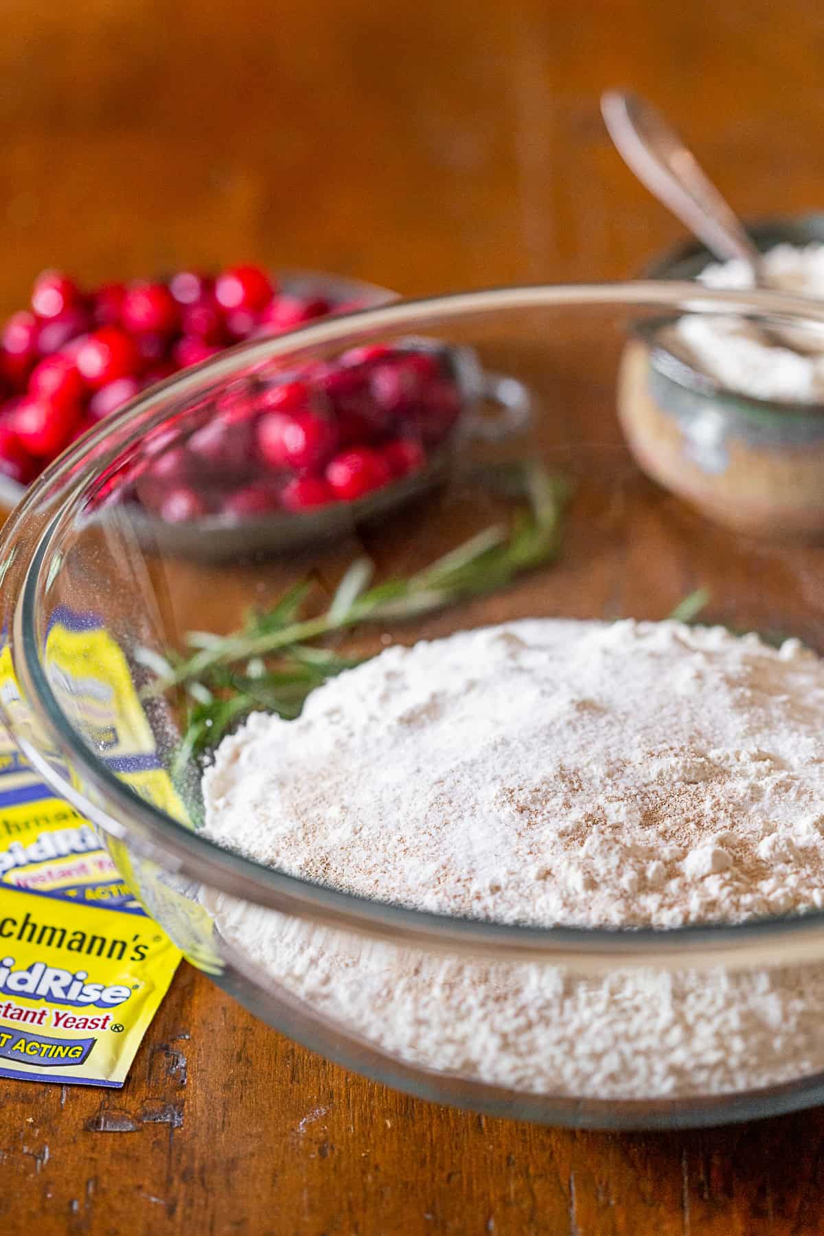 This cranberry rosemary focaccia is easily made from a fresh yeast dough and topped with lots of chopped rosemary, fresh tart cranberries and a sprinkling of kosher salt. Flour and yeast in a glass bowl.