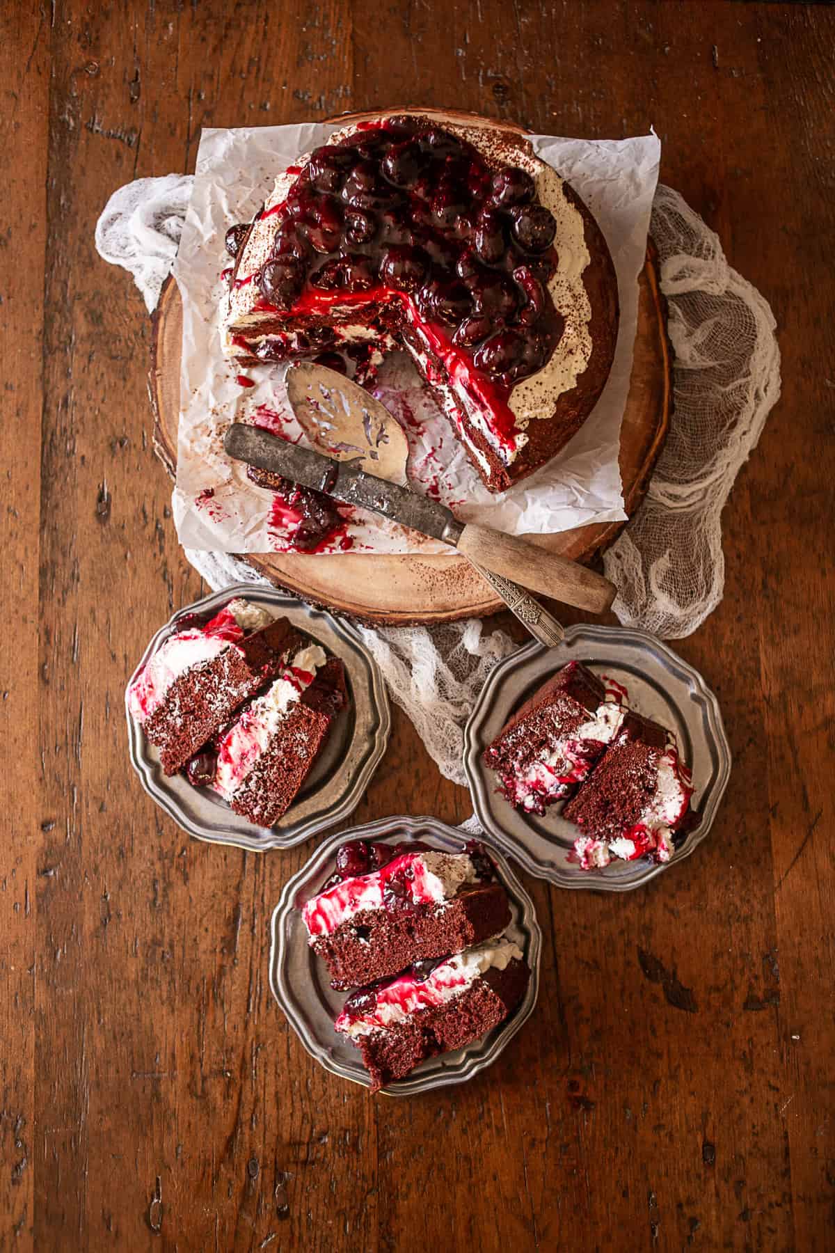 Black Forest Cake on a platter with 3 slices of cake on small plates. 