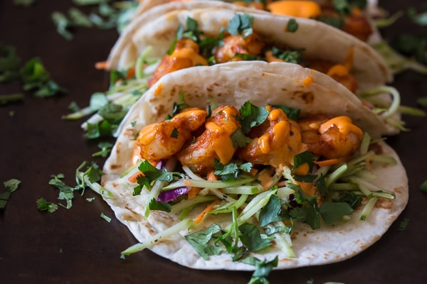 Close up of shrimp and broccoli slaw in a flour tortilla.