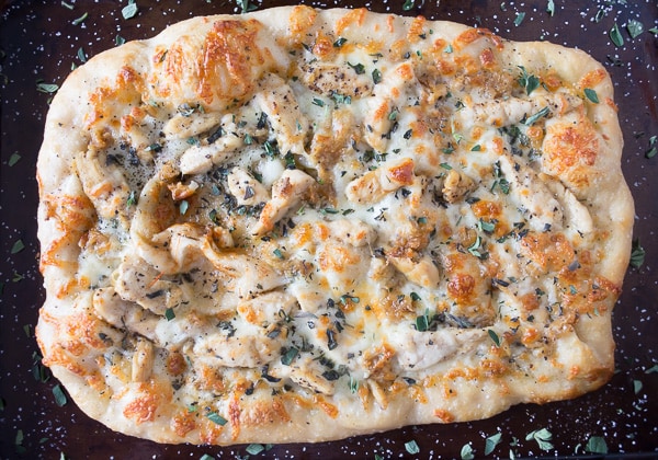 roasted garlic chicken pizza on a black sheet pan