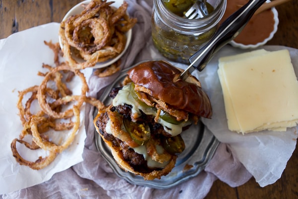 This chorizo beef burger with crispy onion straws is the perfect big mouth burger. Topped with bbq fry sauce, candied jalapeños and American cheese. 