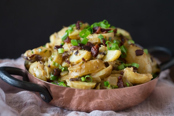 This warm bacon herb potato salad is the perfect winter side dish. It's the perfect balance of tangy and sweet and ready in just about 30 minutes. Made with soft potatoes, bacon, sautéed onions, garlic, fresh herbs and tossed in a tangy apple cider vinaigrette dressing.