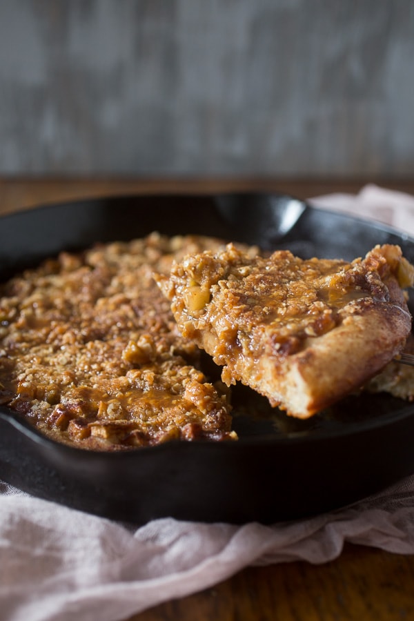 Caramel Apple Crisp Pizza sliced being taken out of the cast iron skillet. 