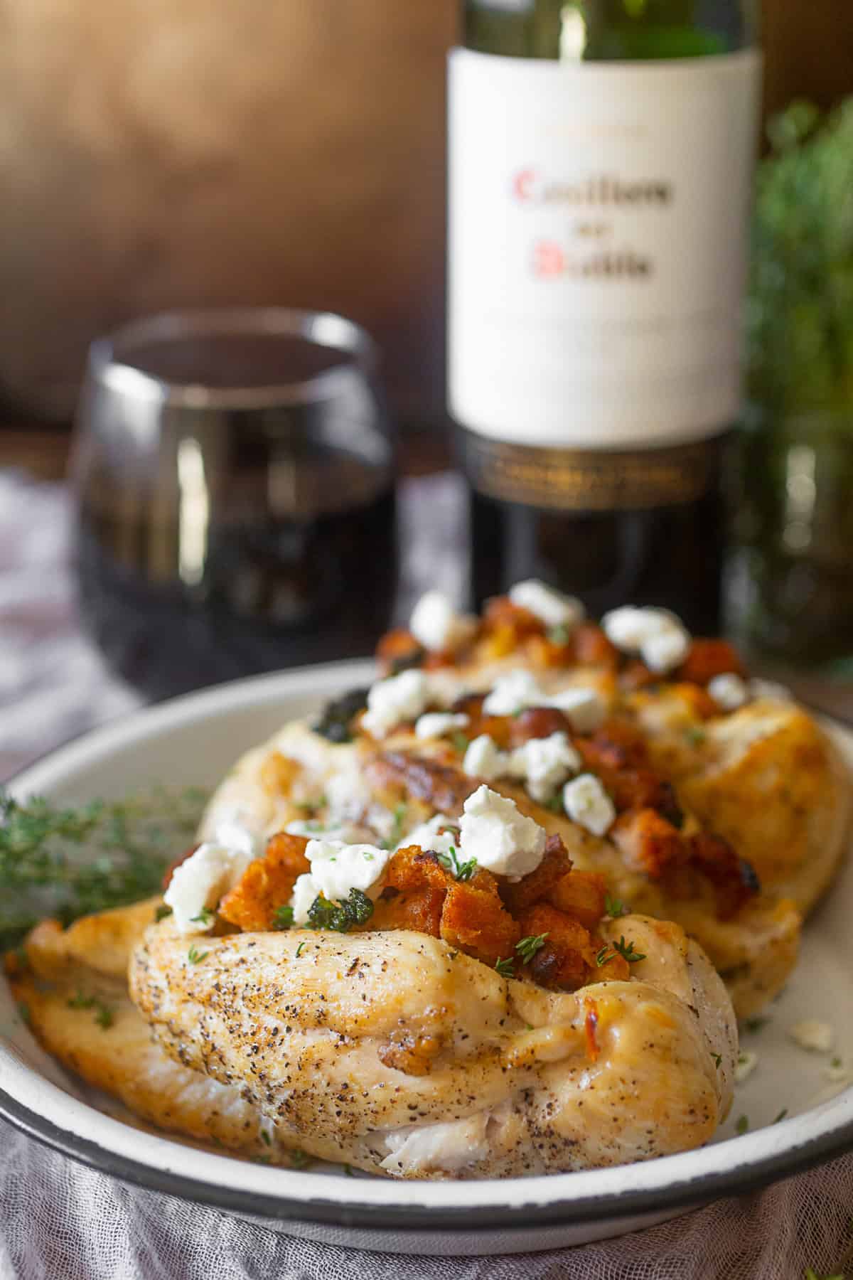 Cornbread Stuffed Chicken  on a plate with wine in the background. 