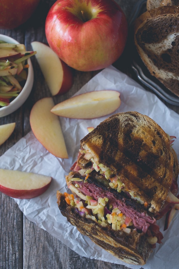 This tangy apple slaw corned beef reuben is the perfect fall sandwich. Perfectly toasted marble rye topped with an apple cabbage slaw, corned beef, melted swiss cheese and lots of homemade Russian dressing.