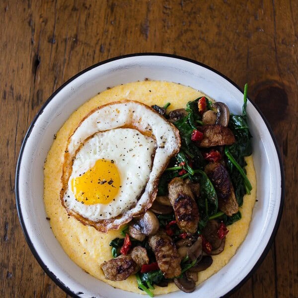 This cheesy polenta sausage breakfast bowl is packed with flavor. It starts with cheesy polenta topped with spinach, sun dried tomatoes, chicken sausage and topped with a crispy fried egg. Never skip breakfast again!