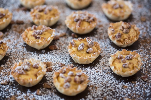 These no bake pumpkin cheesecake phyllo bites are the easiest Thanksgiving dessert ever. Fluffy spiced pumpkin cheesecake filled into crunchy phyllo shells and topped with spiced nuts. You'll love these sweet little bites!