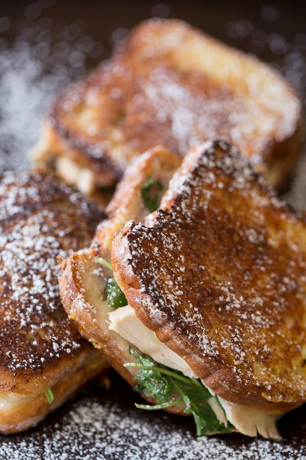 Turkey Monte Cristo on a plate covered with powdered sugar. 