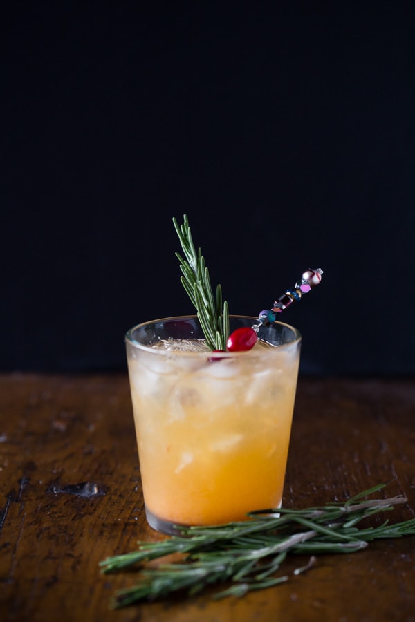 Persimmon Old Fashioned Cocktail garnished with rosemary and cranberries. 