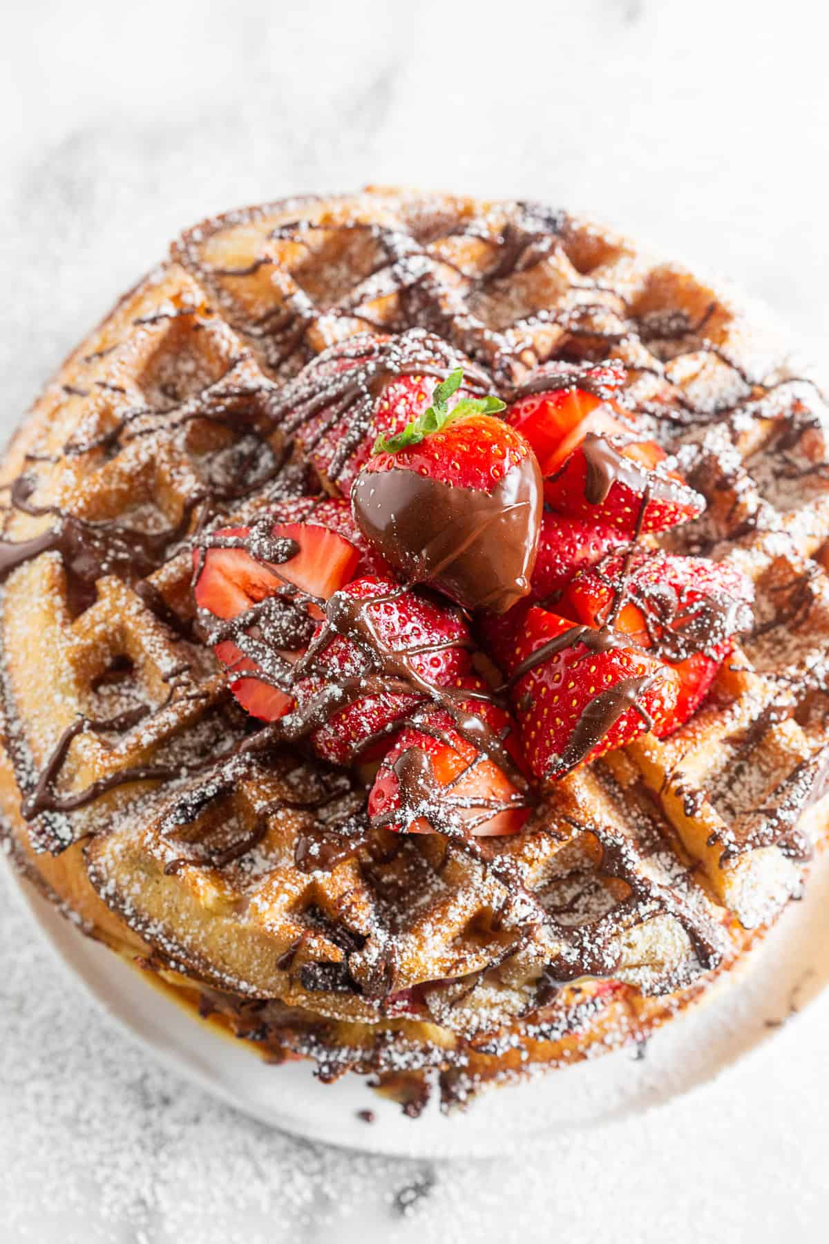 a chocolate covered strawberry waffle sitting on a white plate.
