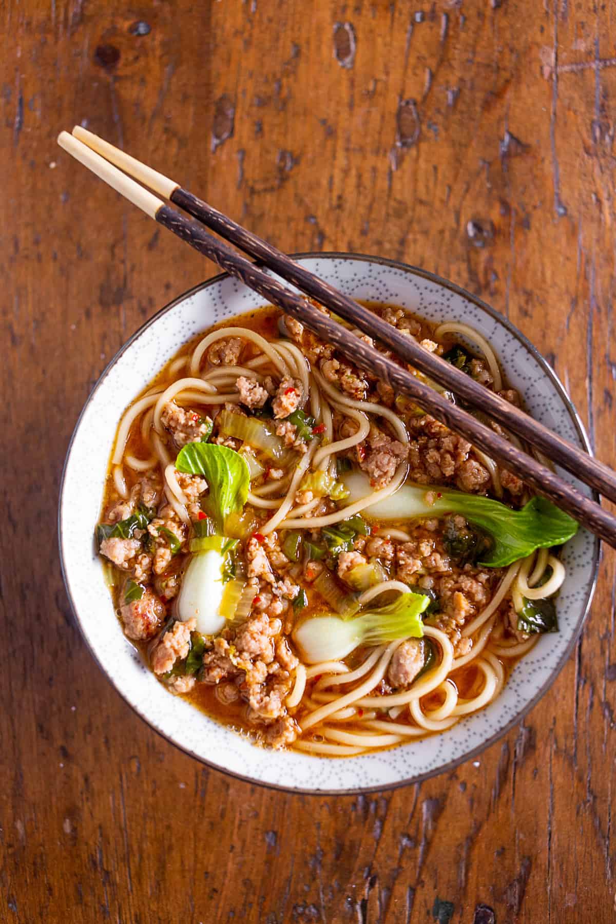 pork noodle bowl in a bowl with chopsticks.