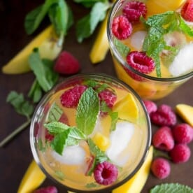 raspberry mango sangria in a glass with fruit around the glasses on a tray