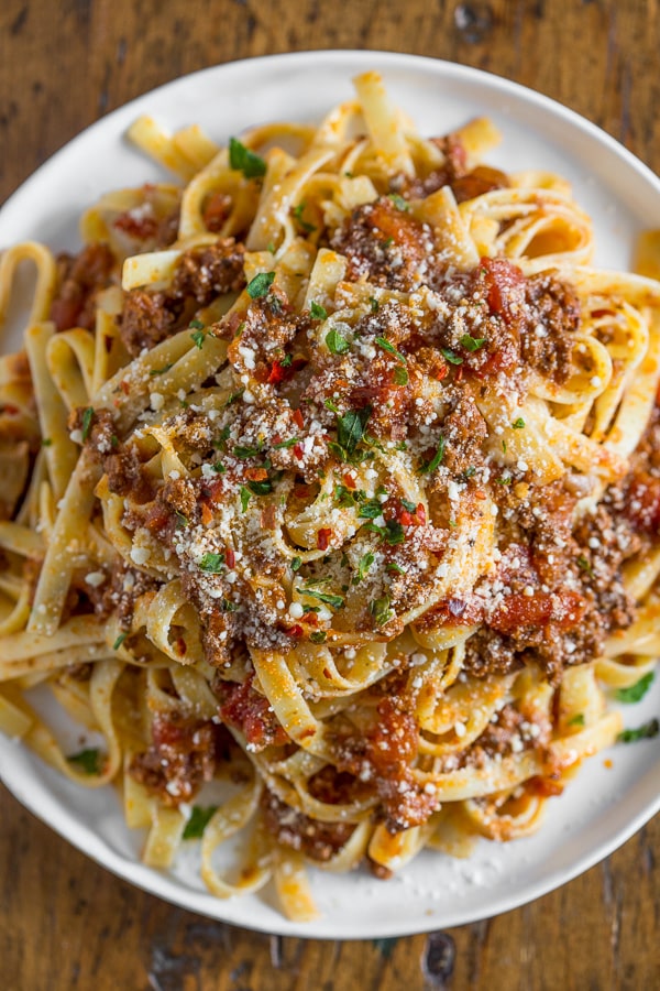 Slow Cooker Parmesan Meat Sauce on a plate spooned over pasta.